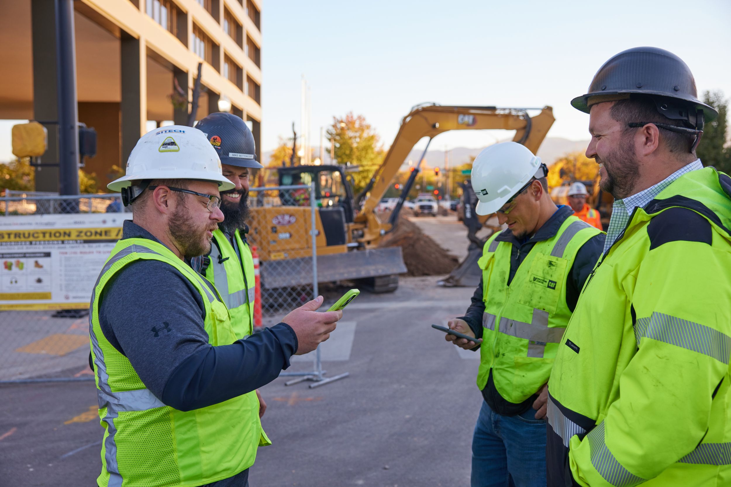 three men standing, talking on a construction jobsite 