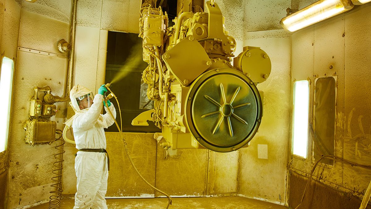Painter applying fresh coat of paint to engine block