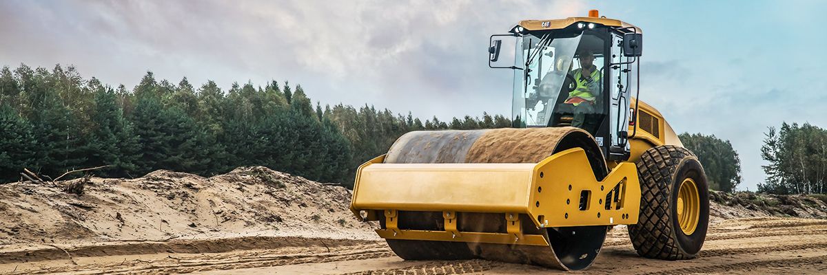 An operator in a Cat Soil Compactor on a job site