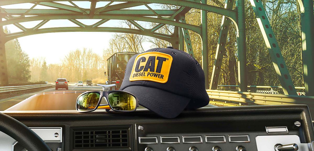 a Cat Diesel Power hat on the dashboard of a truck driving on a highway