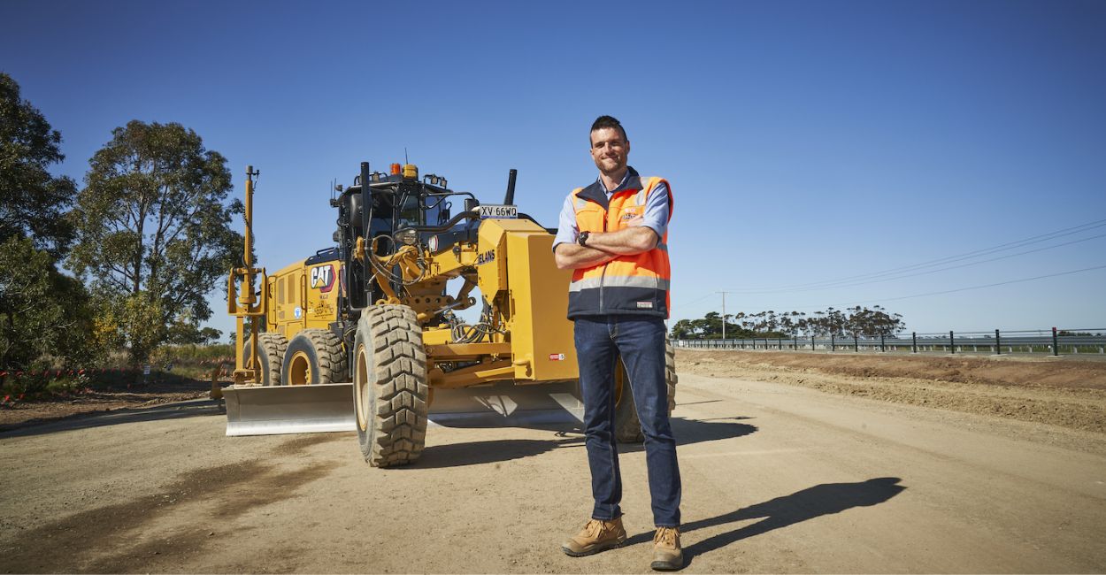 the benefits of leasing cat equipment , man standing in front of motorgrader