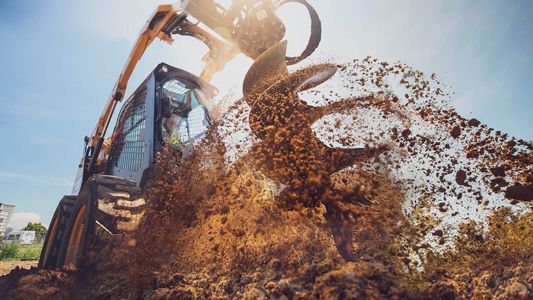 Cat machine attachment digging up dirt.