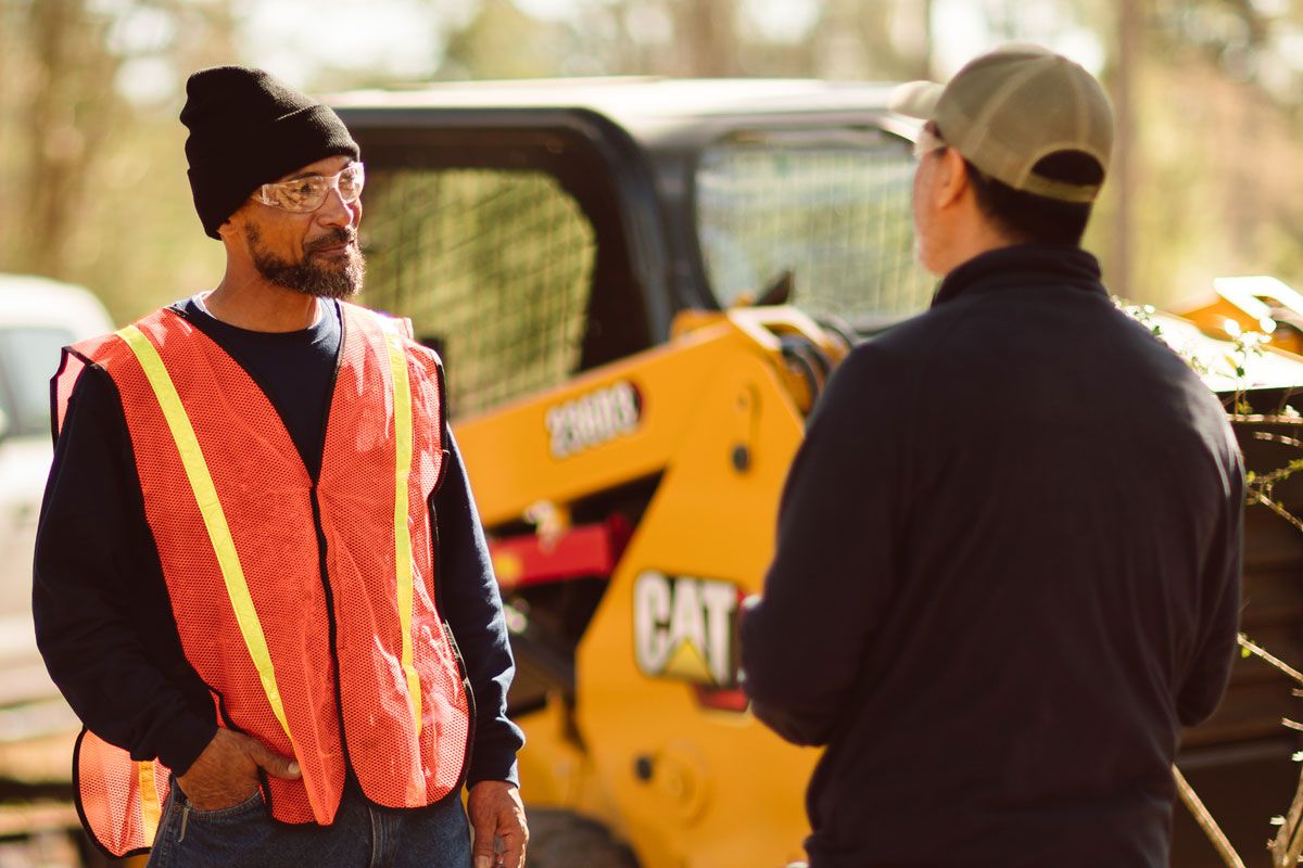 Cat dealer talking with a customer standing near a Cat compact track loader