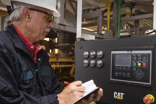 Cat worker in PPE recording information from a CAT hybrid technology control panel