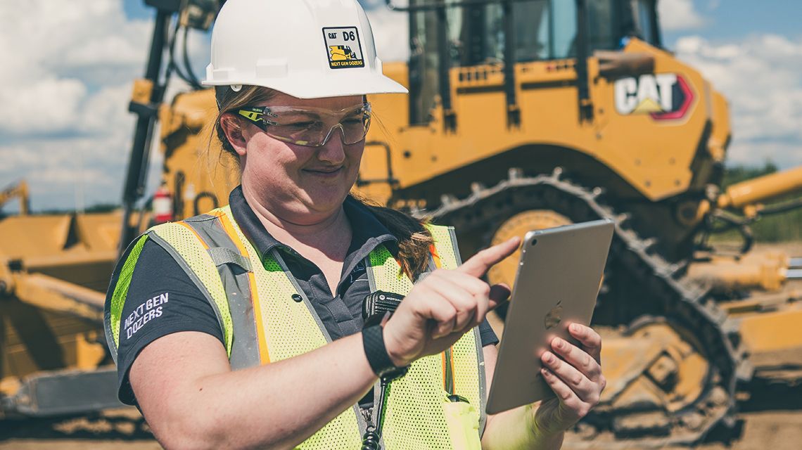 Person utilizing a tablet device with a tractor in the background - Enables Fact-Based Decisions