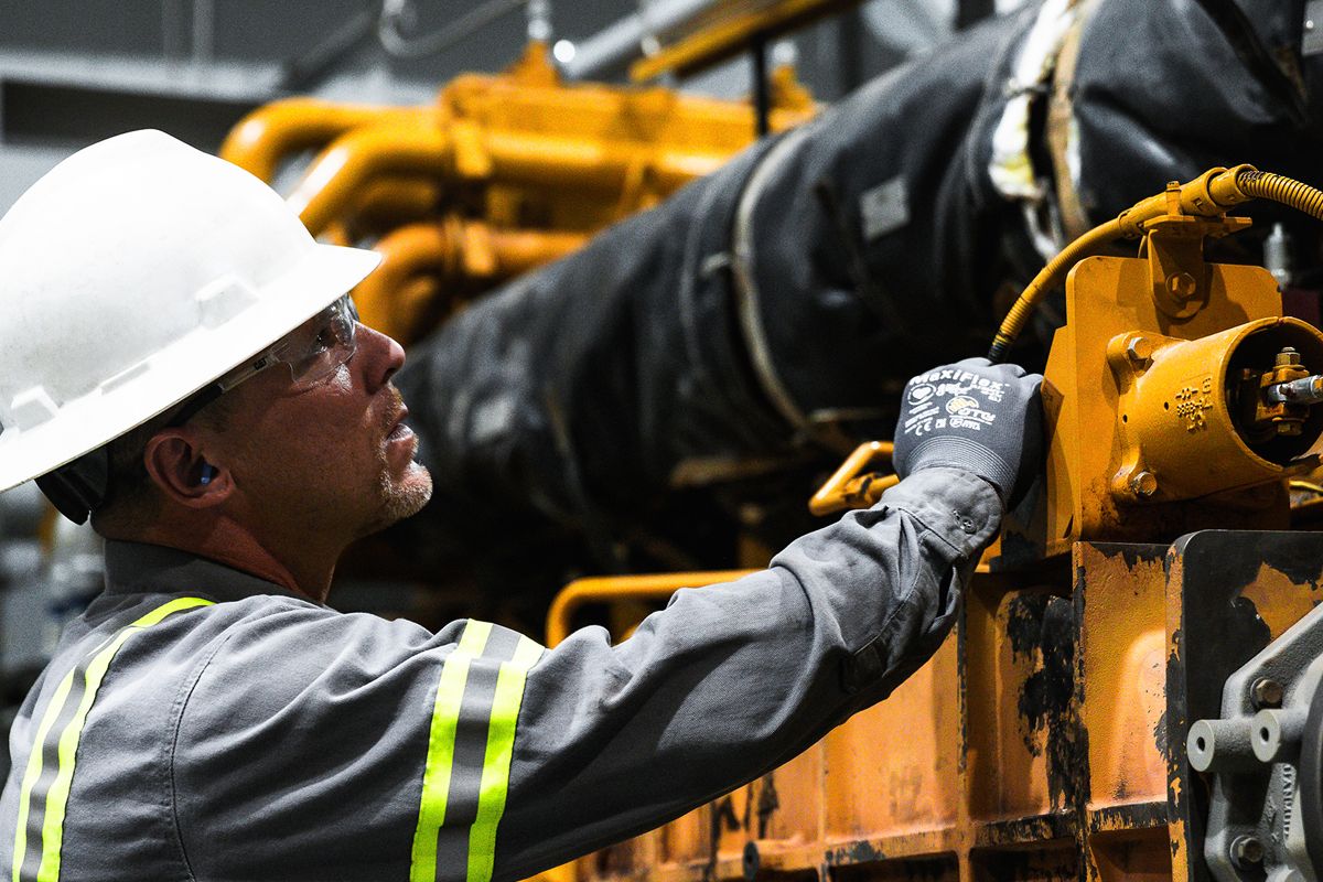 Close up of Cat worker in PPE examining a Cat G3600 A4 Gen 2 Engine