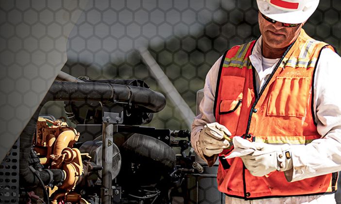 Engine repair person in safety vest holding tool. 