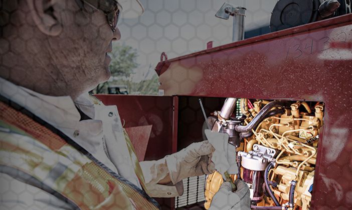 Man in safety helmet and protective gloves cleaning engine components.