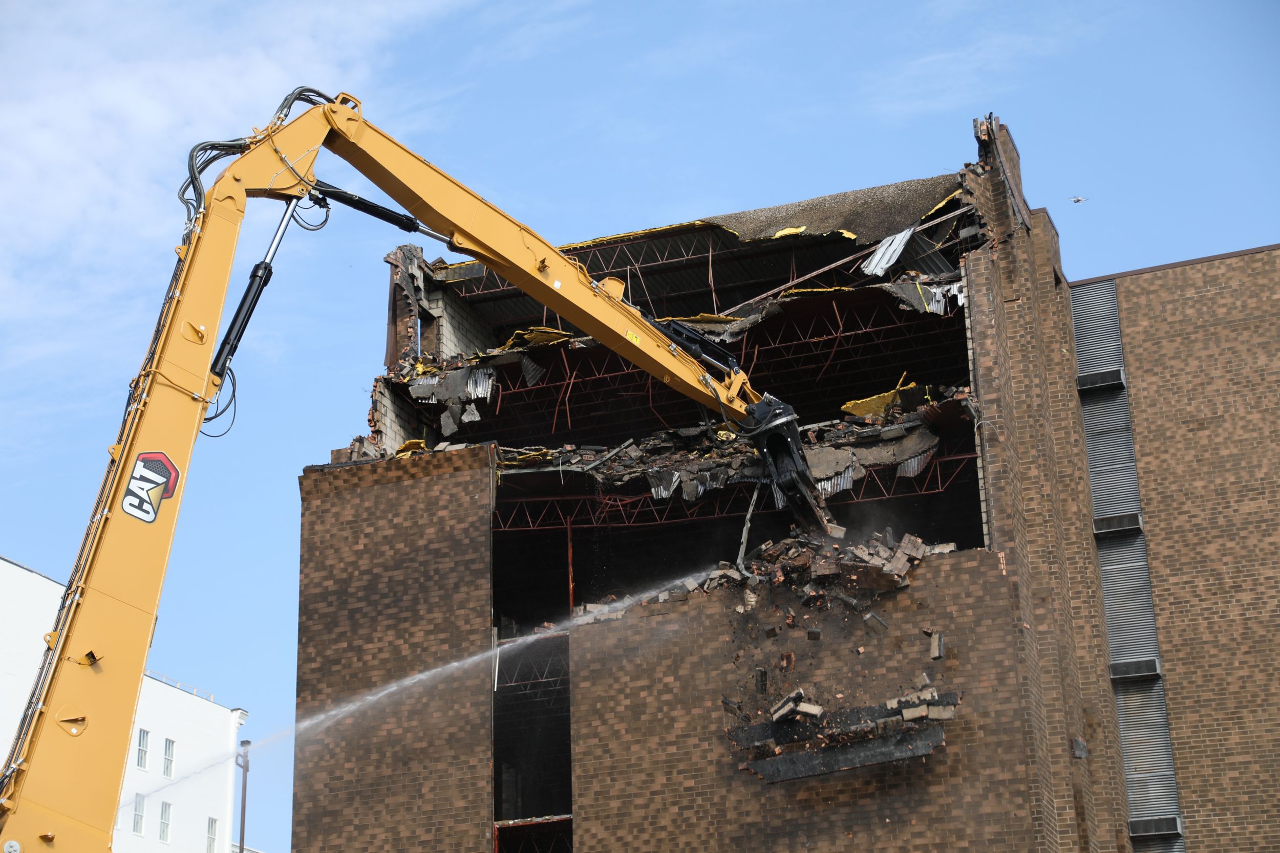 Rozdrabniacz Cat P332 wyburzający budynek z cegły