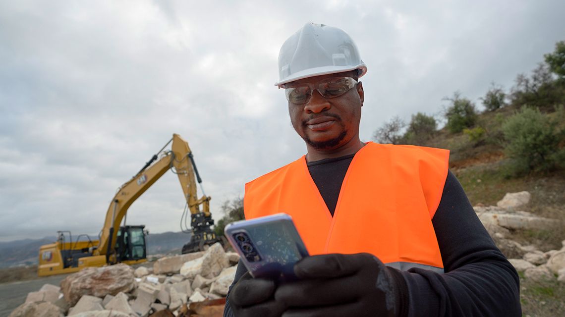 Construction worker holding a smart phone on a job site