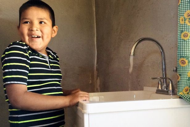 Excited boy next to running faucet