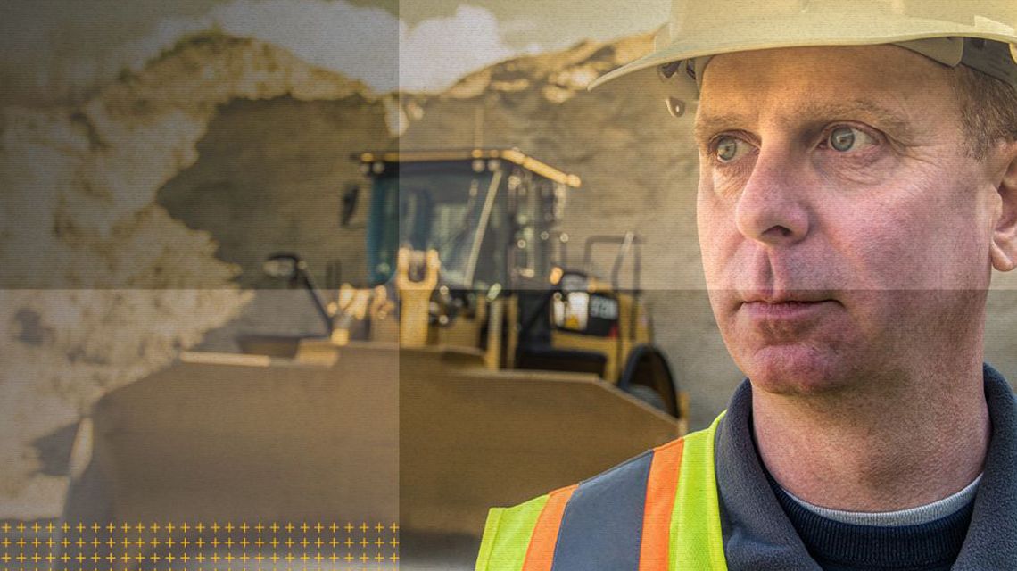 Person on jobsite with a machine at work in the background