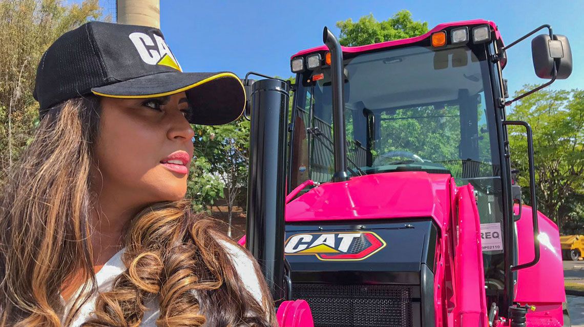 Woman in front of a pink Cat tractor