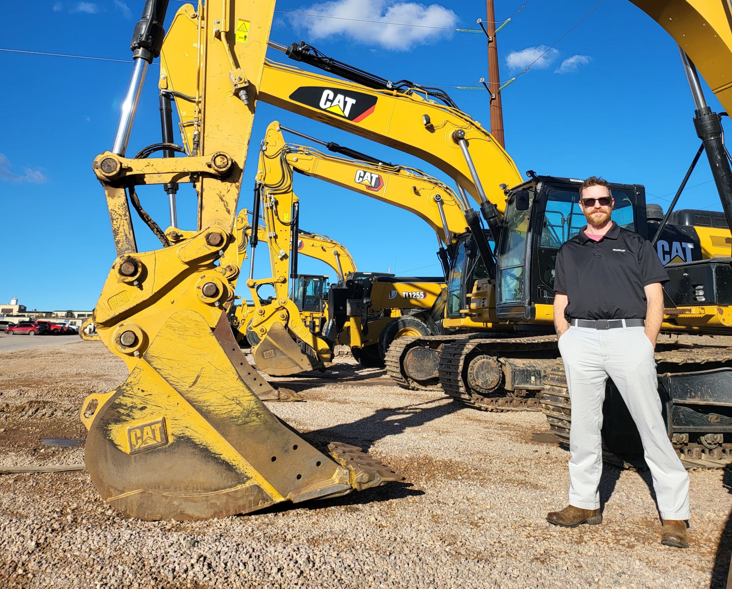 Lars Slentz standing in front of a lineup of excavators