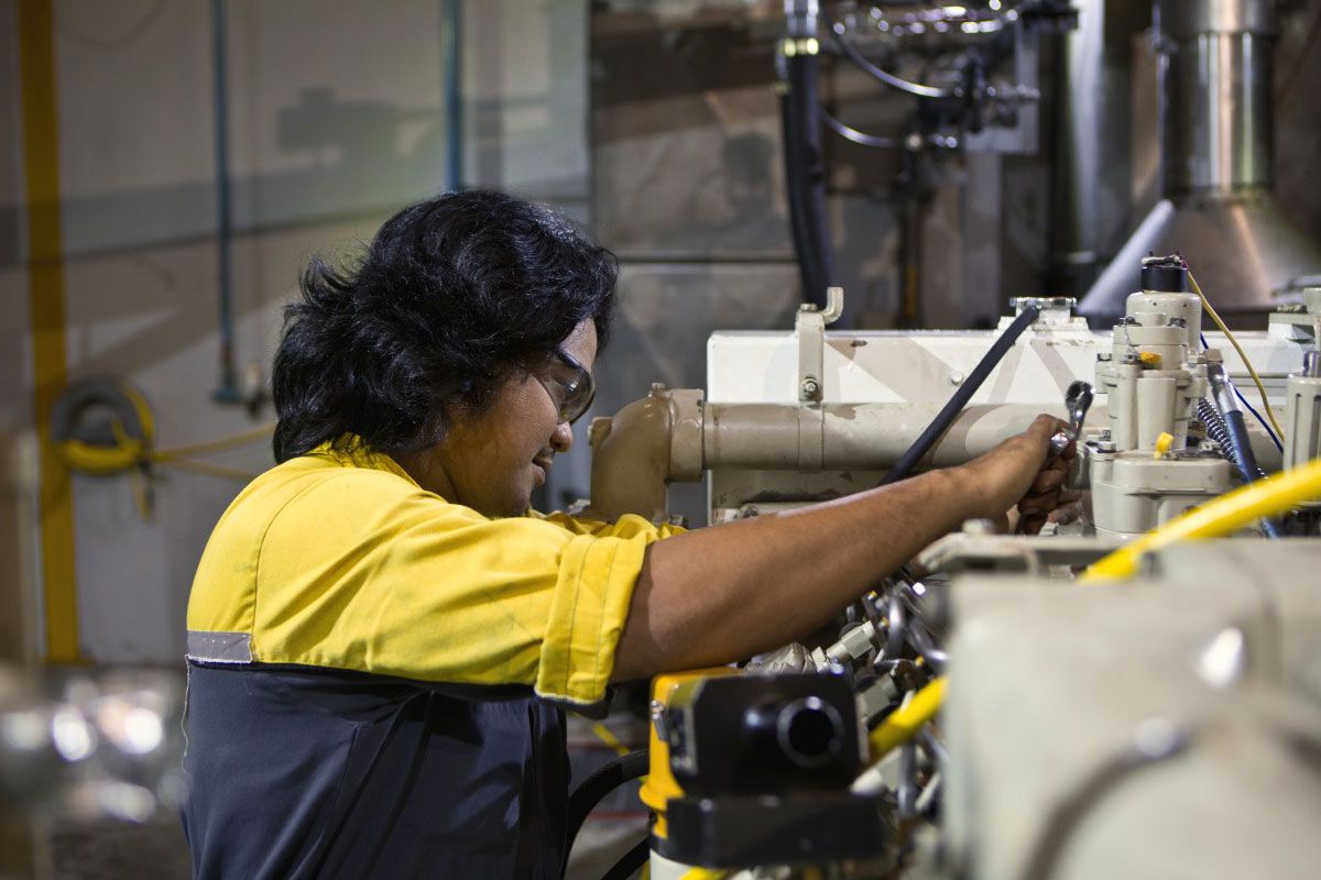 Cat worker wearing PPE performing maintenance on machinery