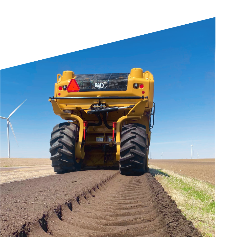 Cat truck driving across dirt and leaving large tire marks behind