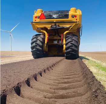 Cat truck driving across dirt and leaving large tire marks behind