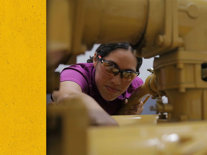 Close up of Cat worker reaching into a Cat engine