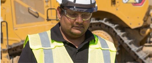 A man standing in front of a Cat dozer