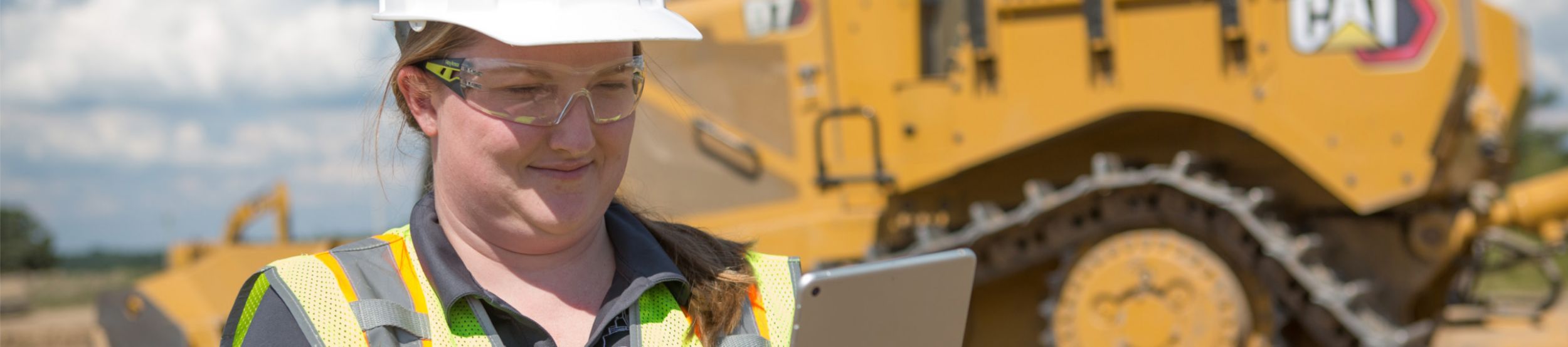 Woman using a tablet while standing in front of a Cat D7 dozer