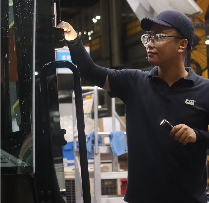 An employee inspects a machine on the production floor