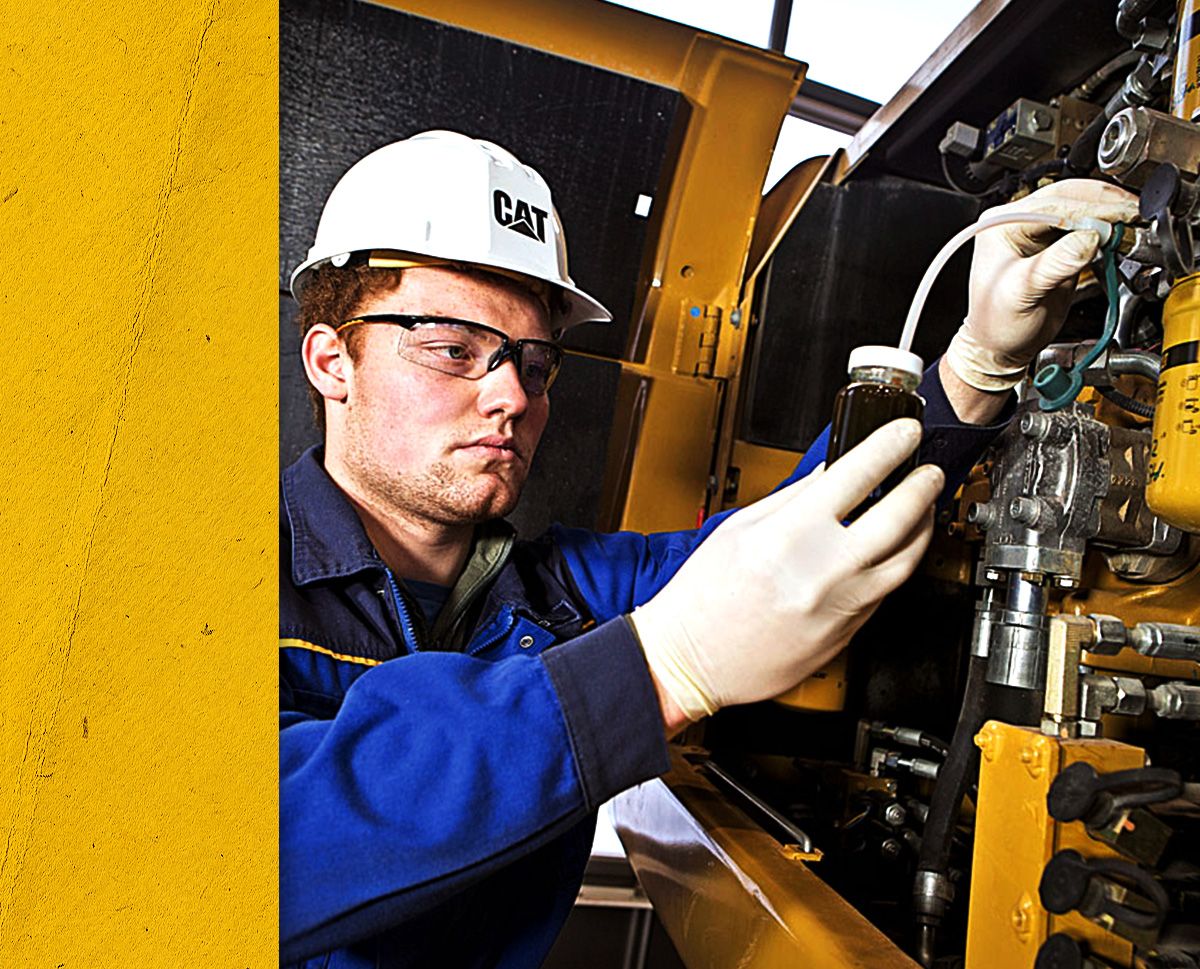 Close up of Cat worker in PPE securing an oil sample from a Cat engine