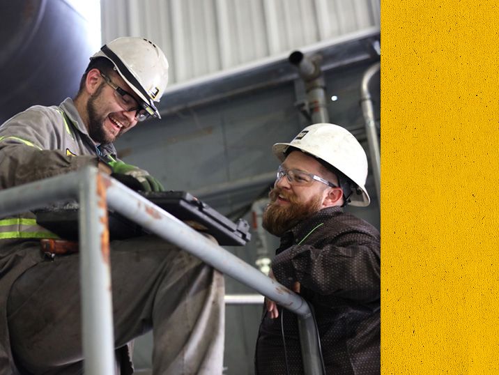 Two Cat Technicians in PPE on a platform laughing