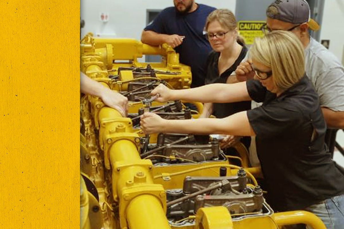 A group of people in PPE learning how to fix a Cat engine