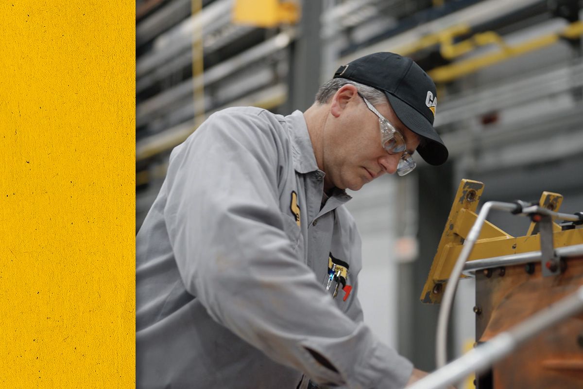 Close up of a Cat worker in PPE working on an engine