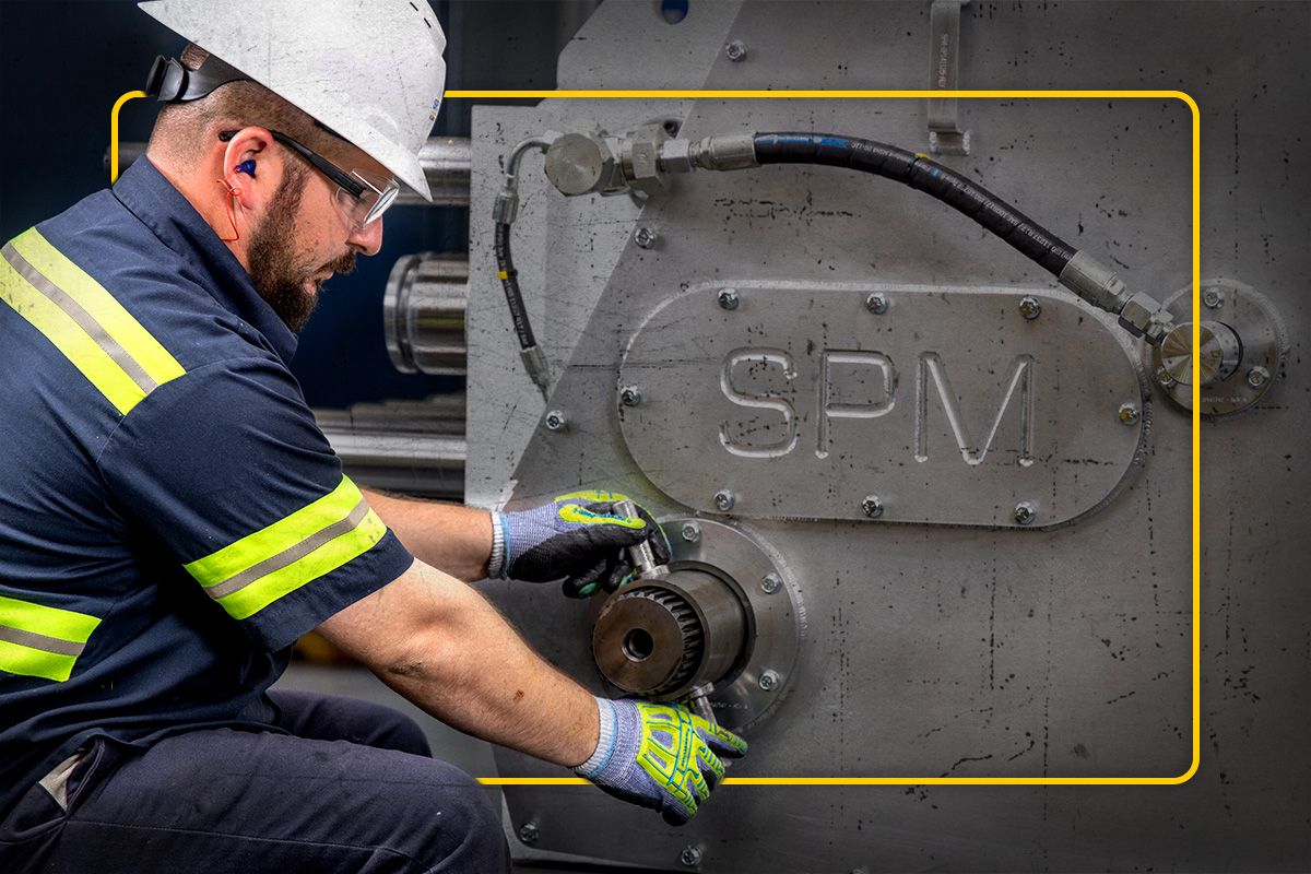 A Cat worker kneeling down to work on an SPM part