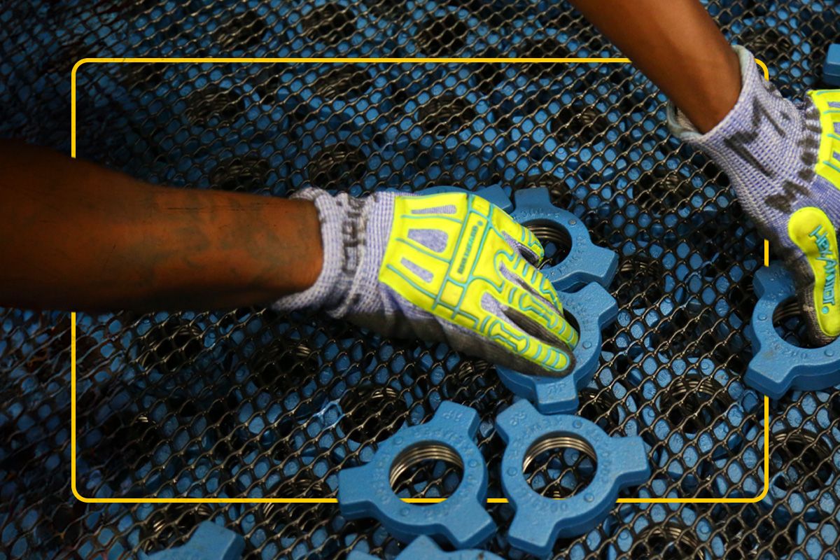 Close up of a Cat worker's gloved hands holding SPM valves over a grate full of valves