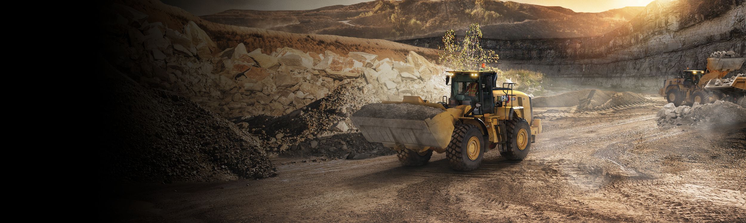 Una pala gommata Cat® durante un sollevamento terra con raggi di sole grafici