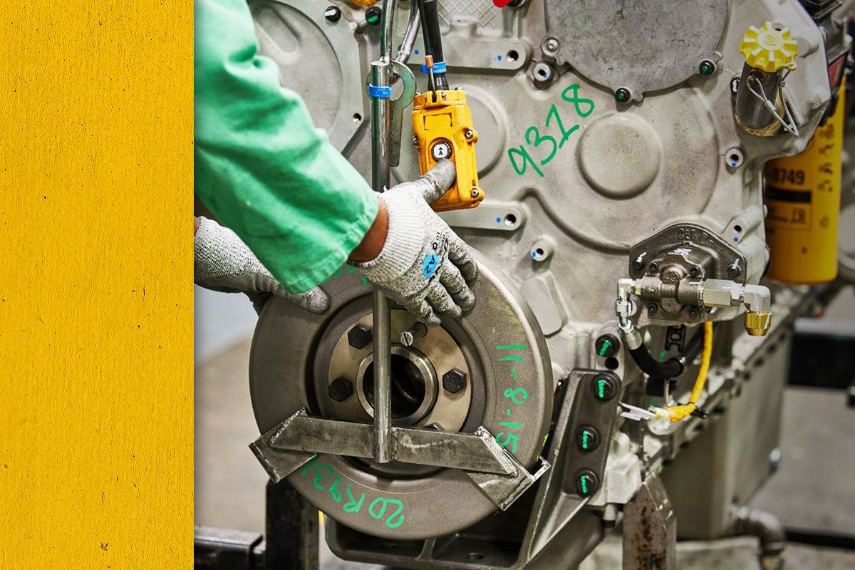 Close up of gloved hands on a reman Cat engine