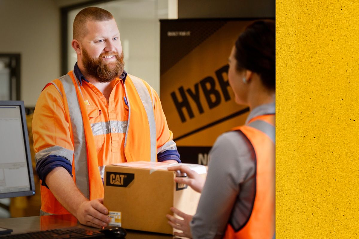 Close up of a smiling Cat dealer passing a box across a counter