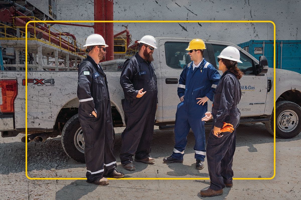 Four Cat workers standing next to a white truck having a conversation