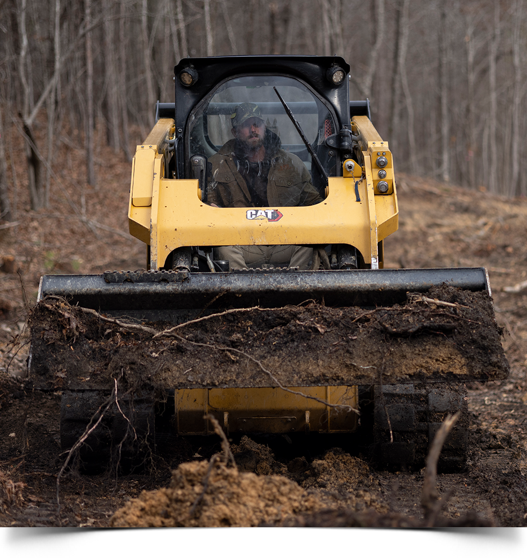 Riley operating a Cat compact track loader on his farm