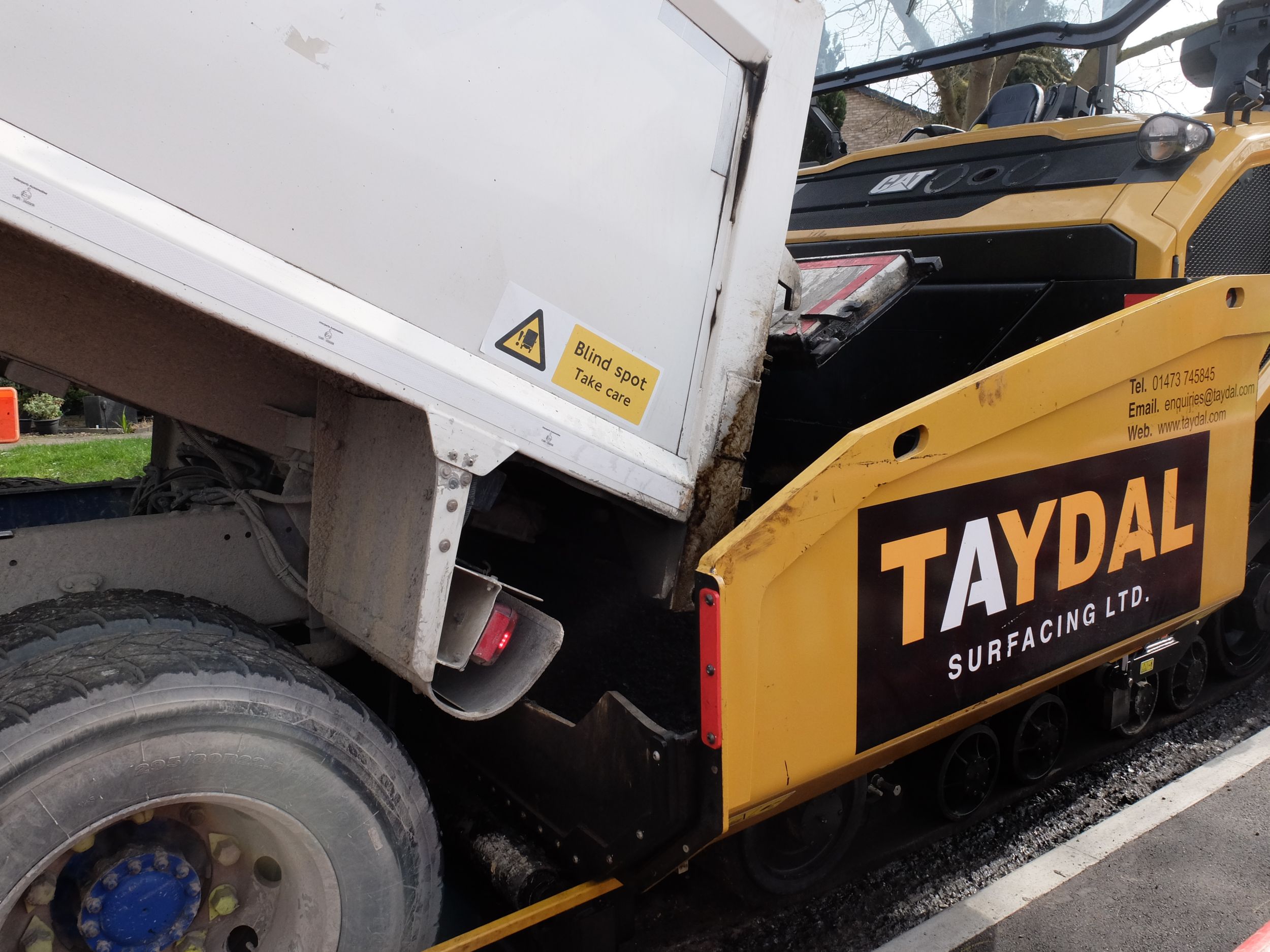 Una flotta di autocarri con cassone ribaltabile ha portato nuovi rifornimenti di conglomerato per alimentare l'asfaltatrice