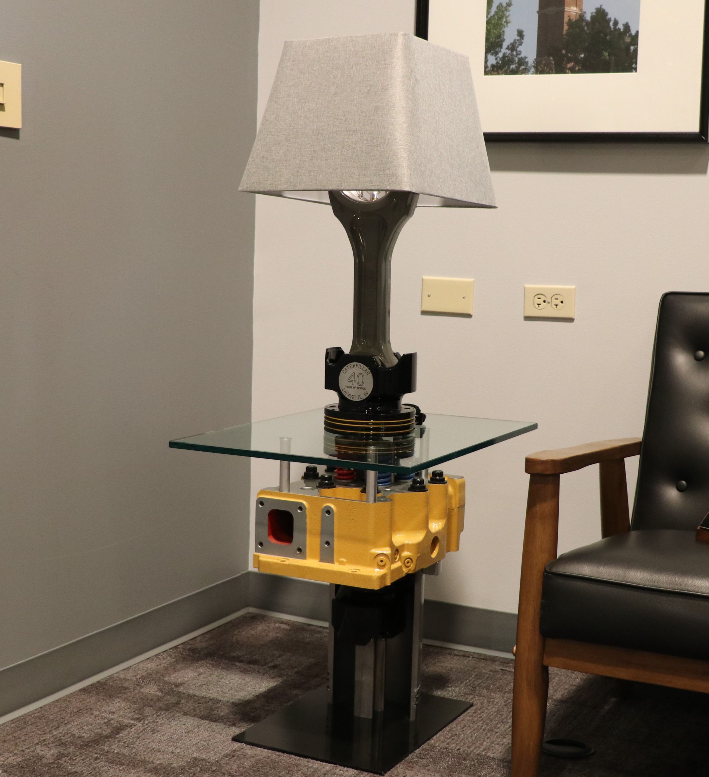 A lamp made using a 3500 piston and rod, sitting on a table constructed from a Cat 3500 head