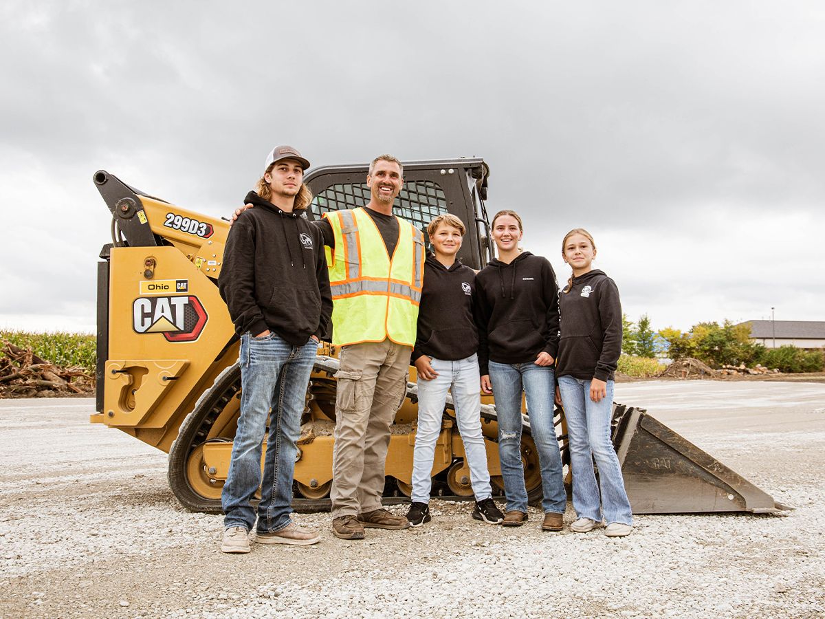 Bronson Koffer of LK & Sons Excavating and his kids next to his Cat 299D3.