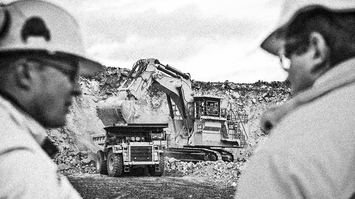 background focus on Mining excavator loading dirt into Mining Truck