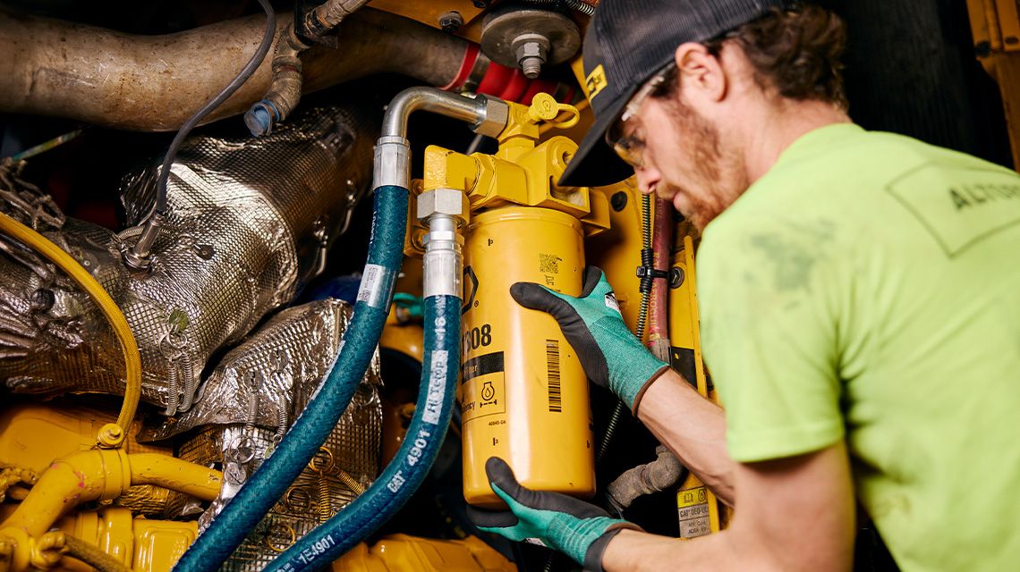 worker replacing filter in a Cat machine