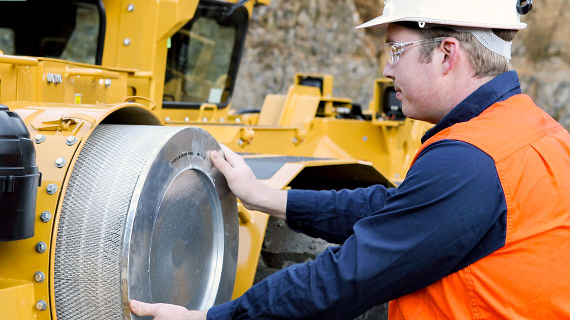 Person wearing orange hi-vis vest holding large Cat air filter
