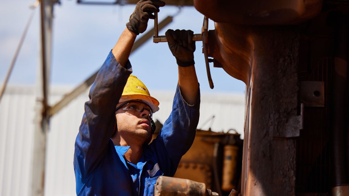 Person wearing yellow hard hat servicing machine