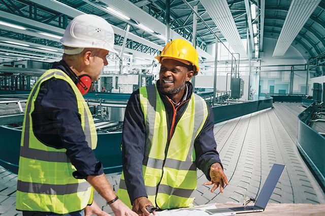 Two workers talking near a desk in a food manufacturing plant