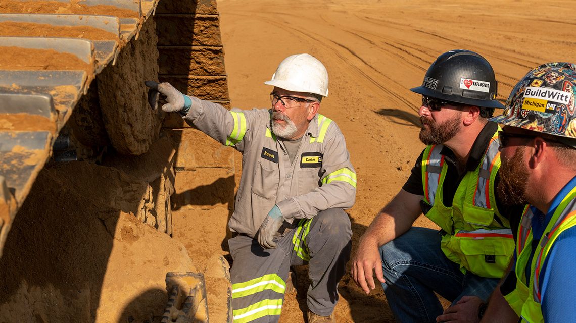 Revendedor Cat com cliente de mineração olhando para um trem de acionamento e um material rodante