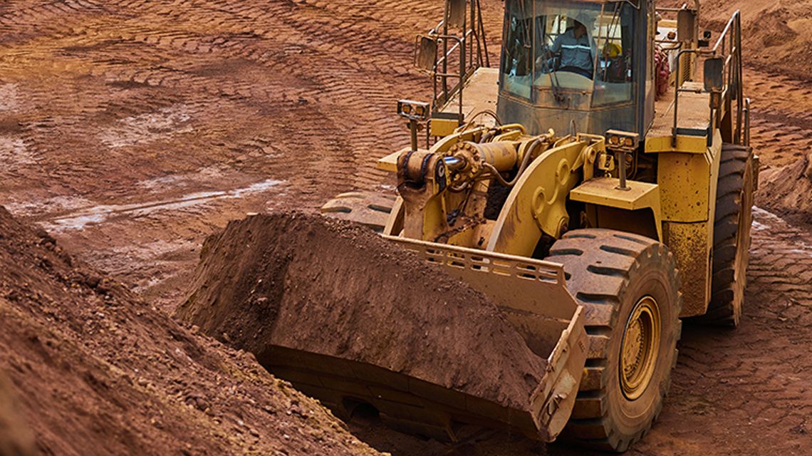 Pás-carregadeiras grandes Cat escavando terra em uma mina com uma caçamba Cat