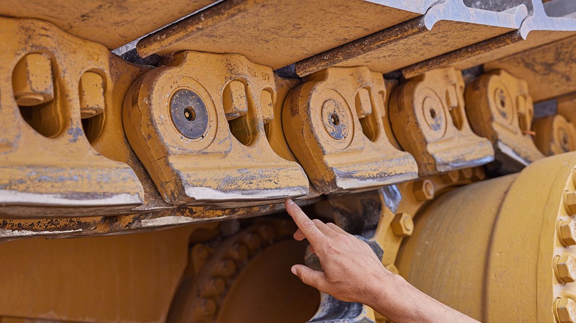 Homem fazendo a manutenção de uma máquina Cat