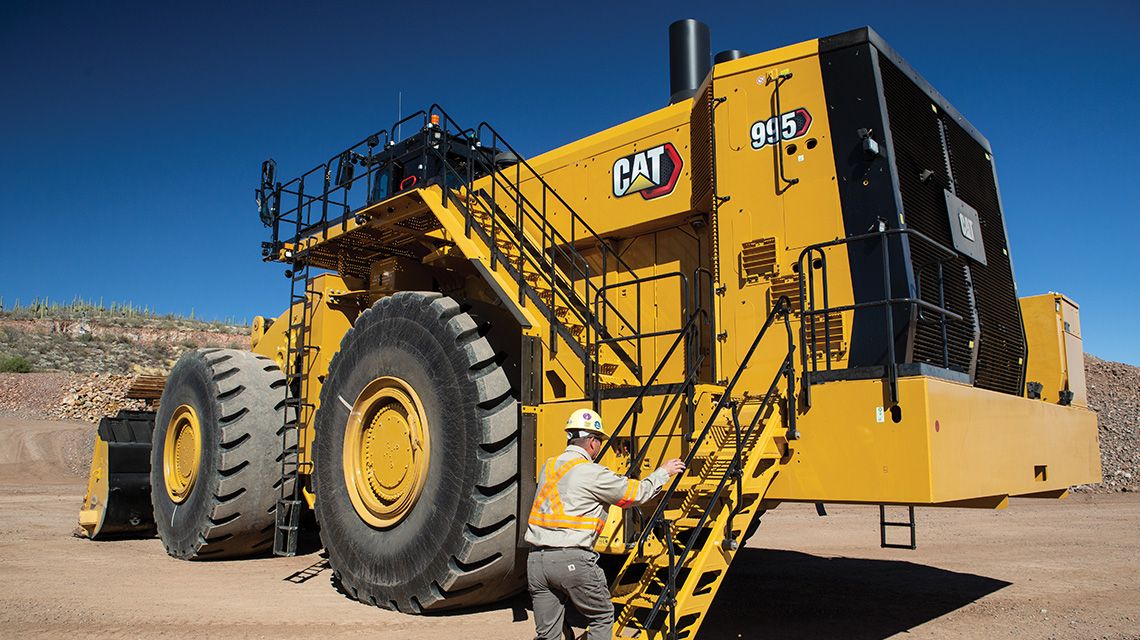Hombre subiendo por escalerilla sobre equipo para la minería