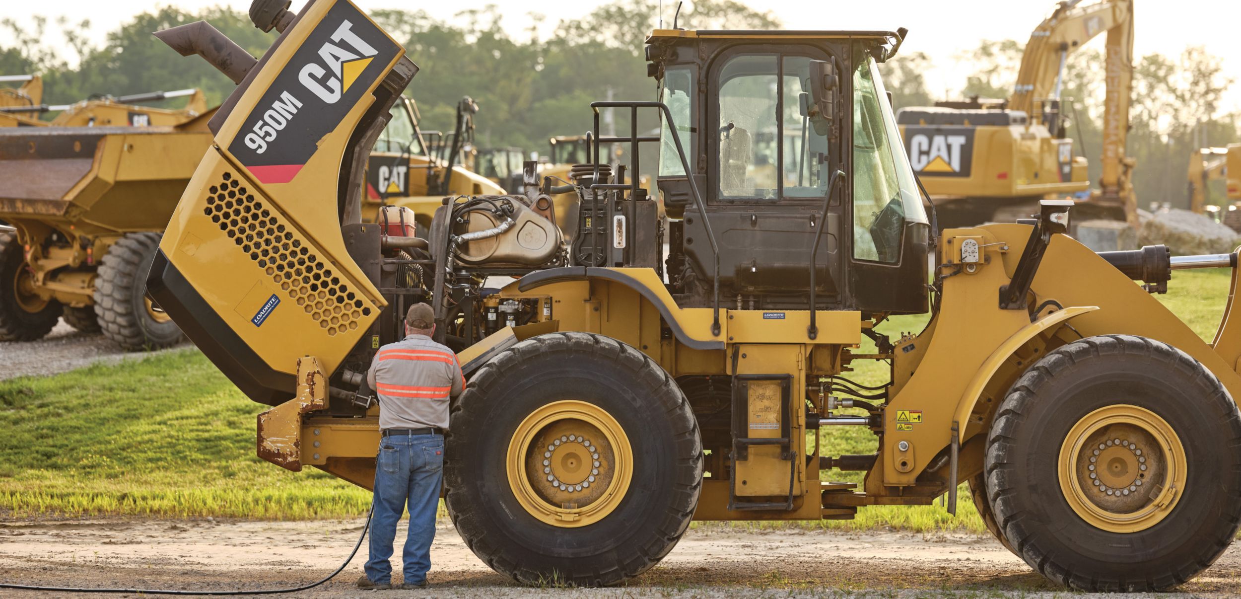 Cat wheel loader with open hood, an operator examining machine