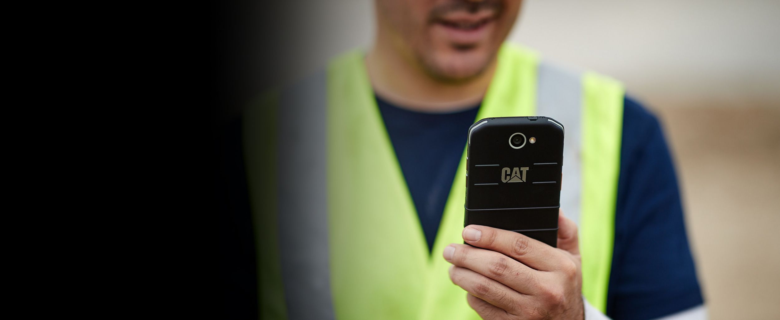 Close-up of a man looking at a phone with a Cat branded case